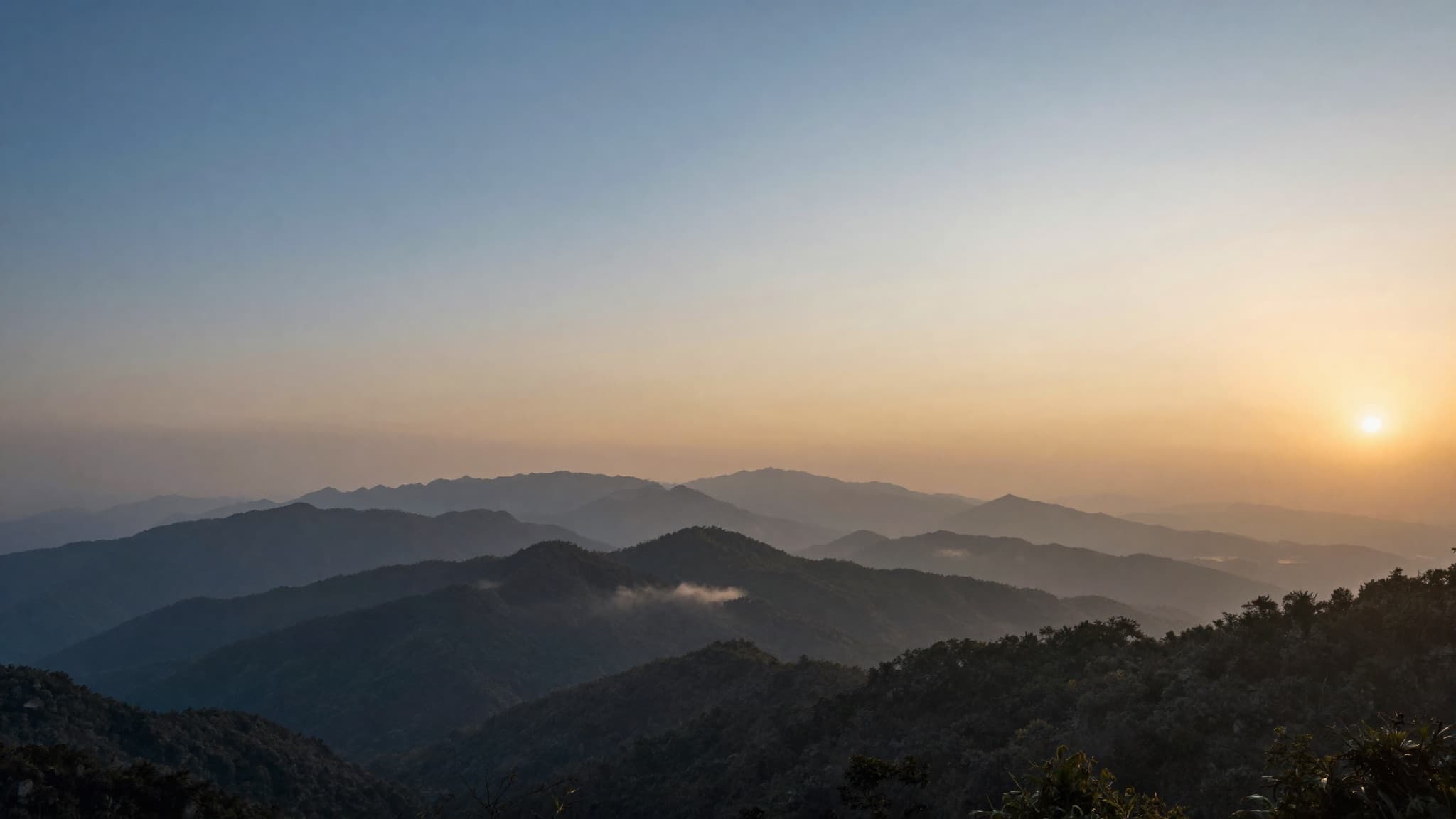 Layered misty mountain ridges glowing at dusk